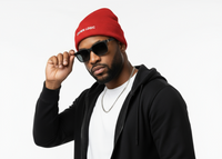 Man wearing a black hoodie, white shirt, red beanie, and sunglasses on a white background